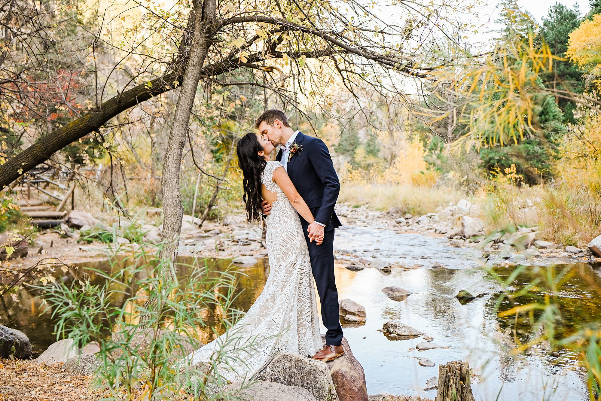 bride and groom standing on rock near creek during the fall at Eldorado Canyon State Park elopement