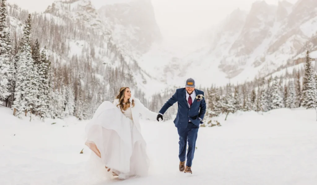 wedding couple walking through a winter wonderland of snow at Dream Lake in Estes Park