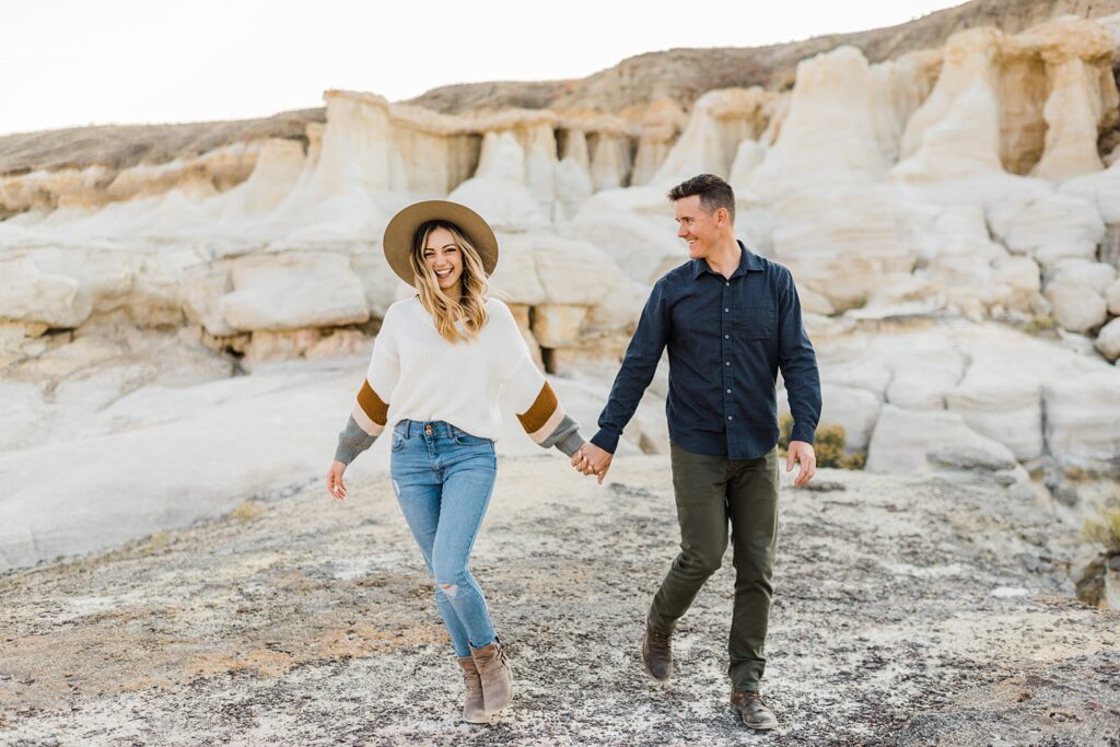 couple holding hands and walking during engagement photos at the Paint Mines in Colorado|couples snuggling during Paint Mines engagement photos near Colorado Springs|couple kissing surrounded by colorful rocks at the Colorado Paint Mines during engagement photos|couple passionately kissing in the Paint Mines during couples pictures in Colorado Springs|couple sitting on a blanket and kissing in the Paint Mines|couple standing side by side looking opposite directions during Paint Mines engagement session|black and white photo of couple holding hands and walking in the Paint Mines during Colorado unique engagement photos|woman tossing her dress while kissing fiance during colorful Paint Mine engagement photos in Colorado|couple twirling next to the colorful rocks of the Paint Mines during engagement photos in Colorado|man snuggling woman from behind during Colorado engagement photos|man and woman's hands intertwined during engagement photos in Colorado|black and white of woman sitting on man's lap and laughing during Colorado Spring engagement photos|black and white of engaged couple with arms around shoulders laughing during Colorado engagement photos|engaged couple laying on blanket in the Paint Mines for couples photos|woman snuggled up into man's chest with engagement ring during couples photos in Colorado|couple walking next to colorful rocks during Paint Mines engagement session|couple walking and laughing during engagement session at the Paint Mines in Colorado|couple holding hands and walking away in-between tall colorful rocks during Paint Mines engagement session