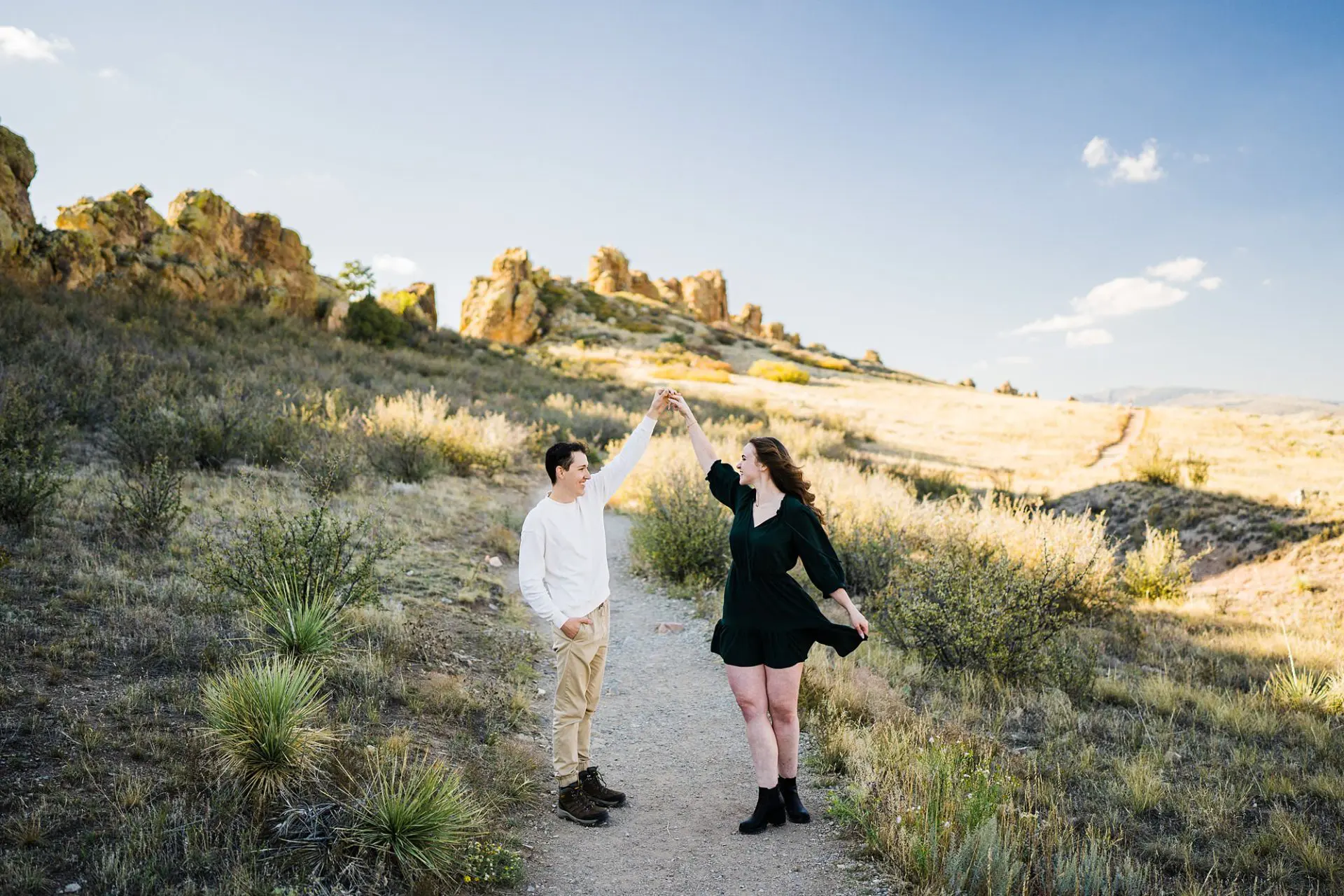 couple walking across field with jagged rock formations in the background at devil's backbone winter elopement location in colorado