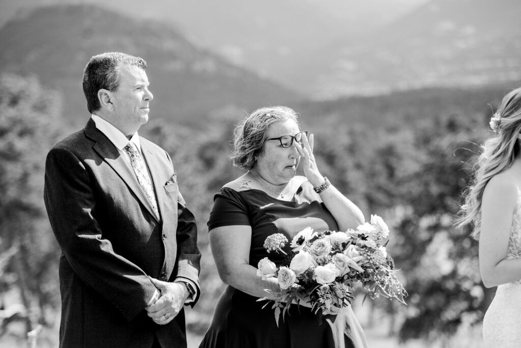 mother of the bride wiping a tear from her eye during intimate wedding ceremony in Estes Park