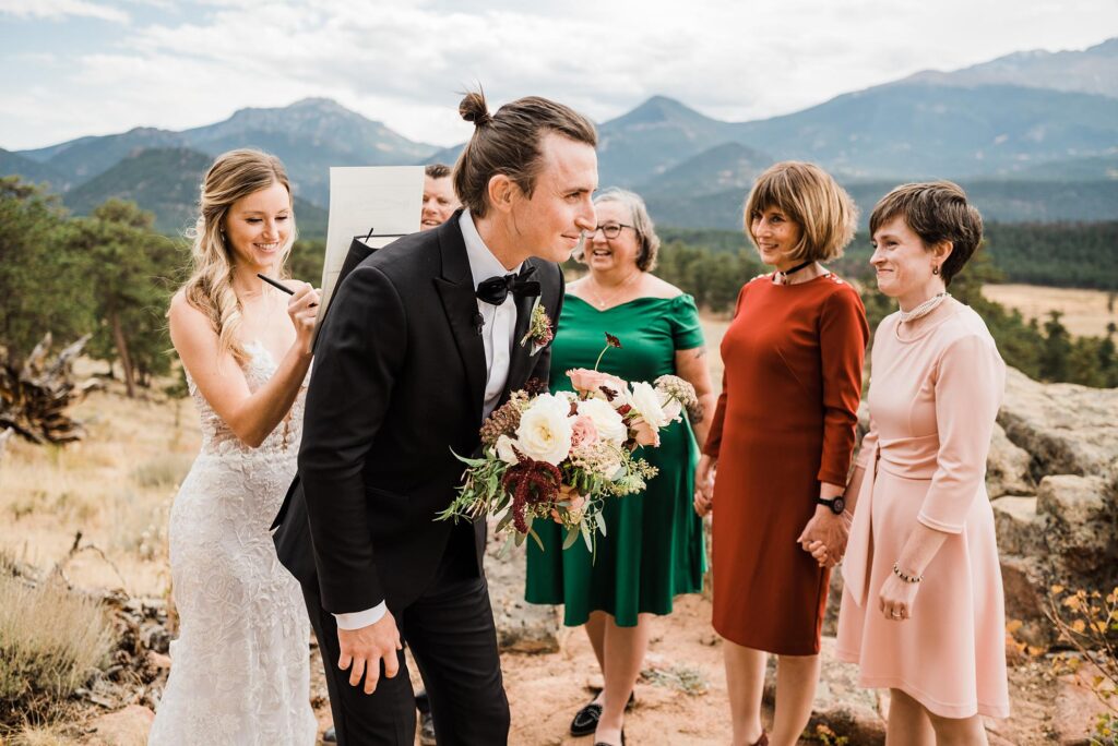 bride using groom's back to sign marriage license after intimate wedding in Estes Park