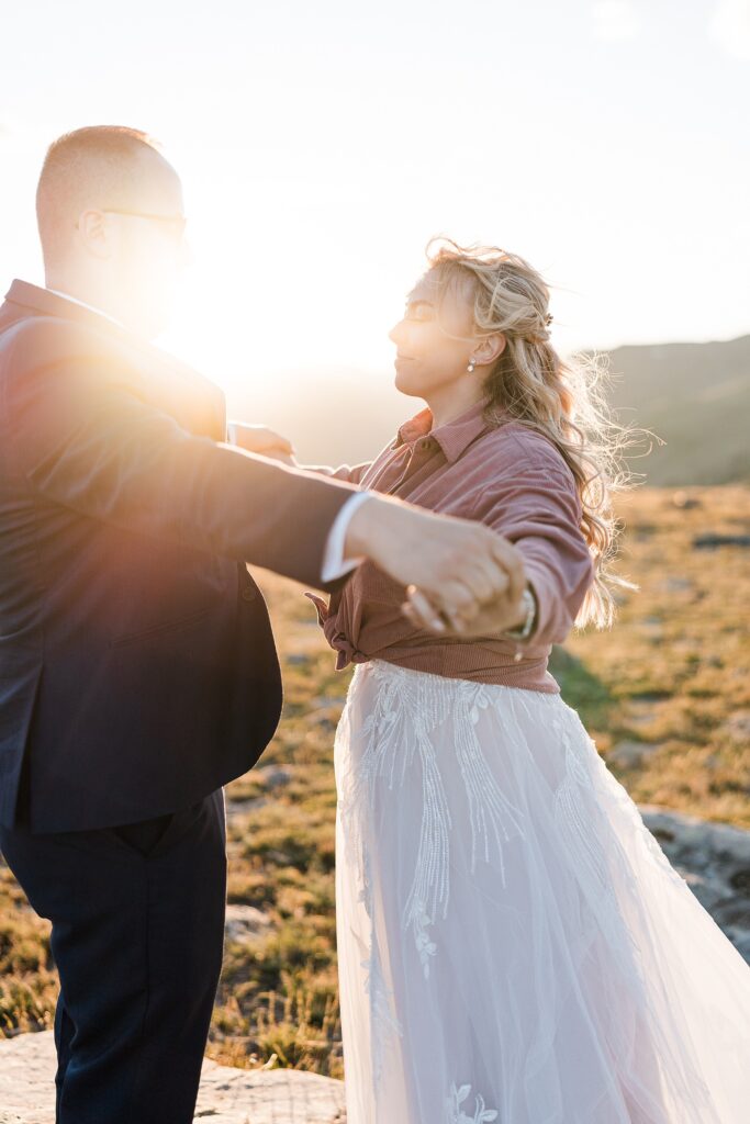 bride and groom holding hands and closing eyes with the sun setting in the background on Trail Ridge Road